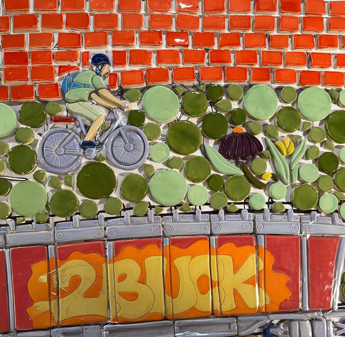 Tile of a cyclist riding past a coneflower.