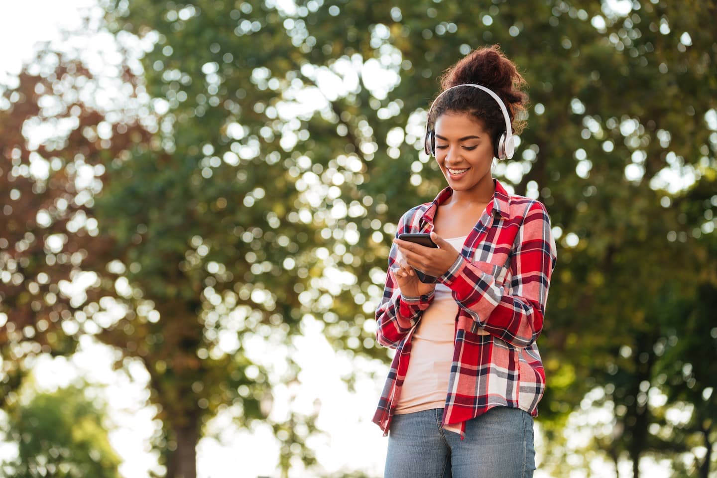 Person listening to phone audio with headphones, smiling