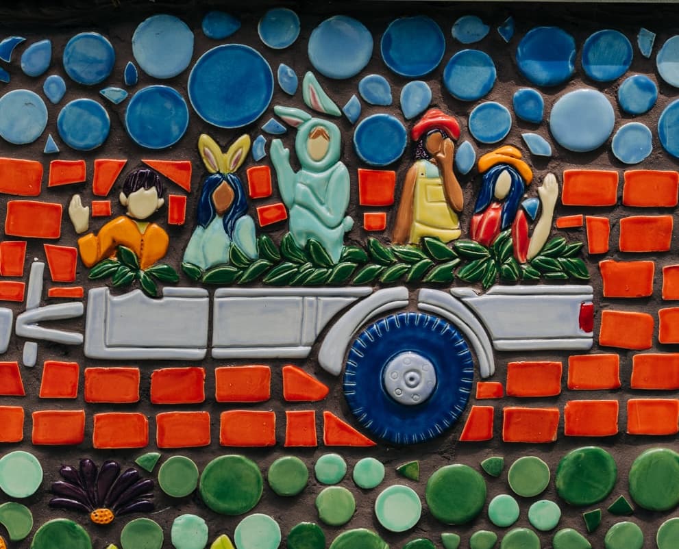 A mosaic panel of five children in bunny ears riding in the decorated bed of a pickup truck during an Easter parade