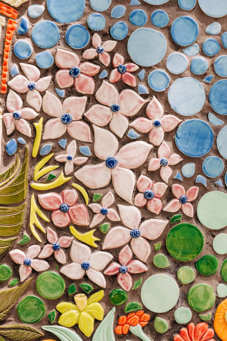A close-up of the mosaic's pale pink ceramic flowers with cobalt-blue centers, set among blue and green glazed pebble tiles