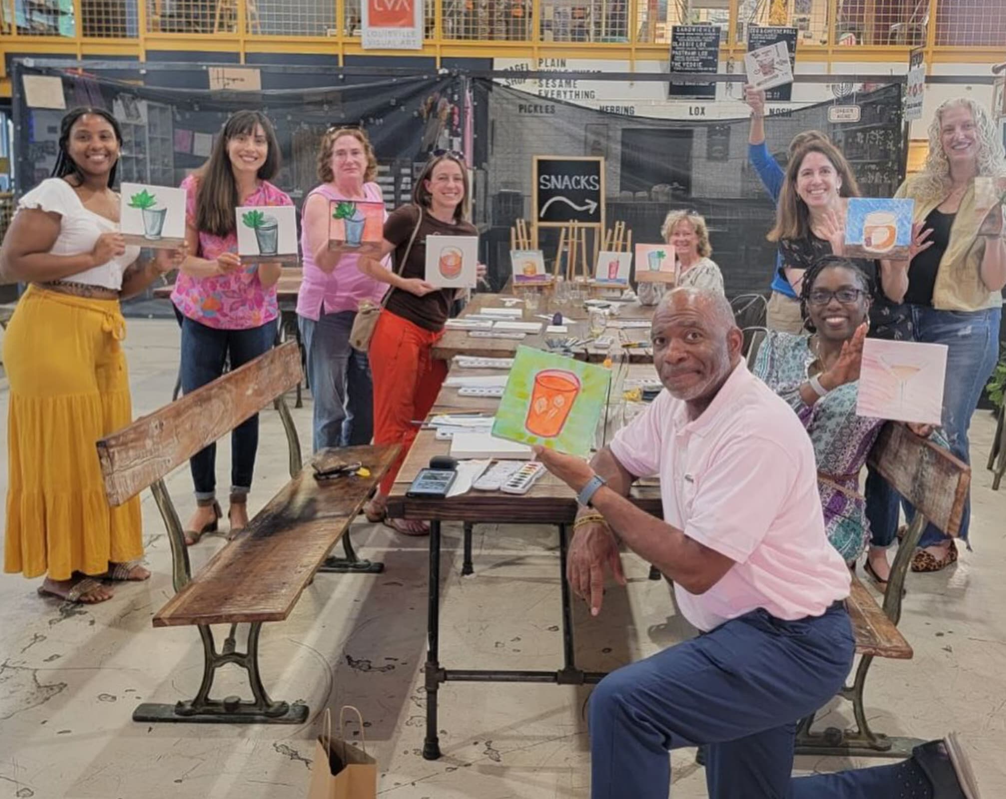 A group of painters displaying their finished canvases to the camera