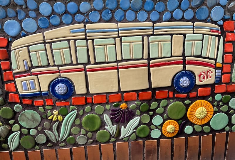 Tile of a TARC bus riding past coneflowers and marigolds